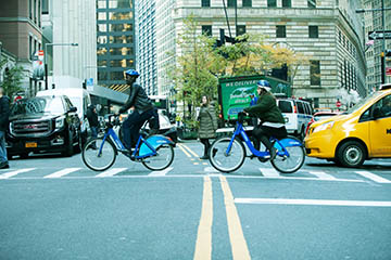 Two bikers crossing a city street