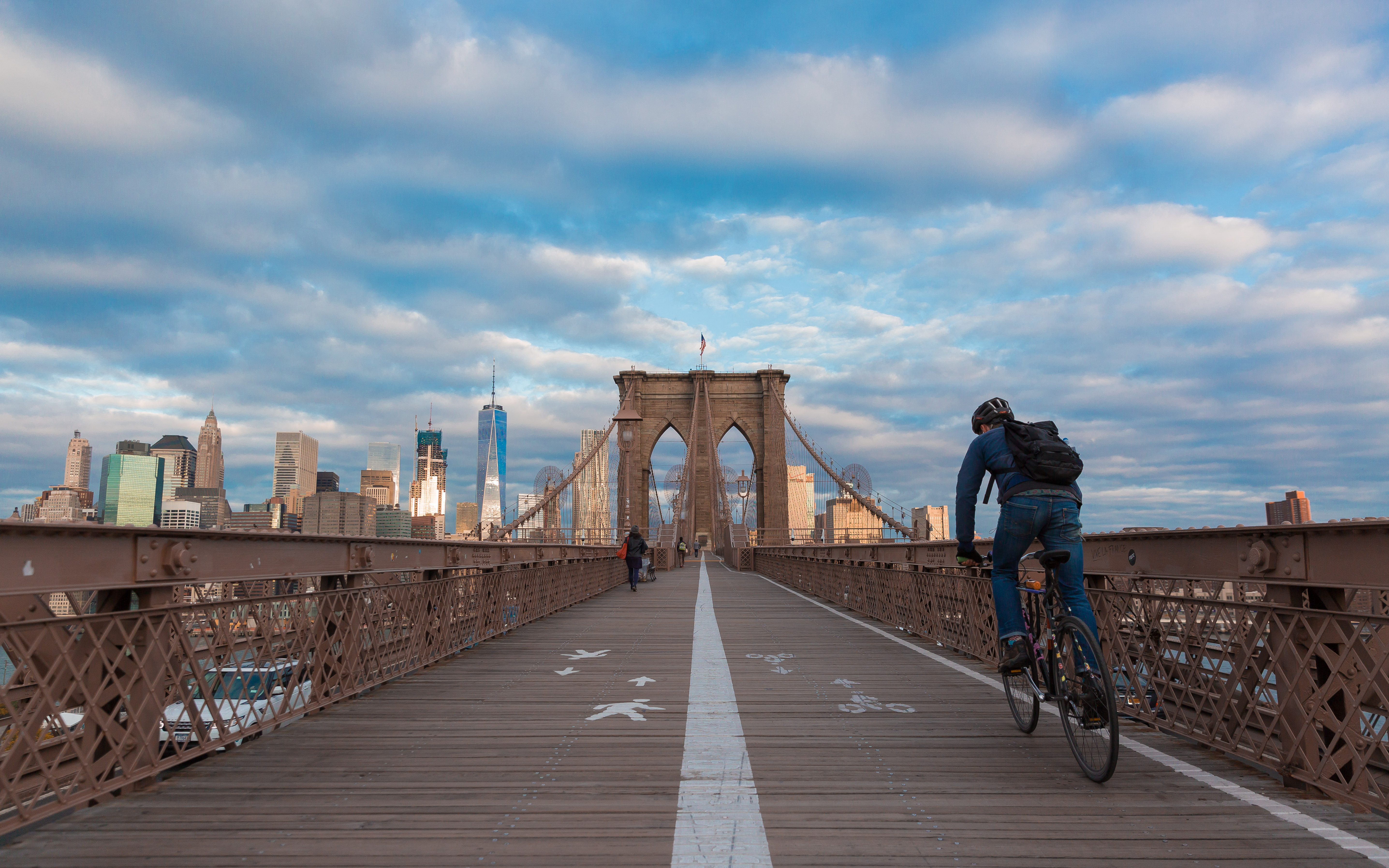 Person with a backpack biking over the Brooklyn Bridge.